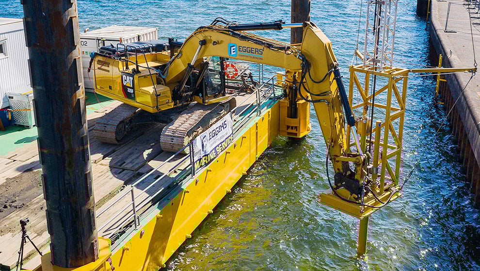 Bagger von Eggers Marine Service auf Ponton beim Absenken einer Konstruktion ins Wasser für Wasserbau und Kampfmittelbergung